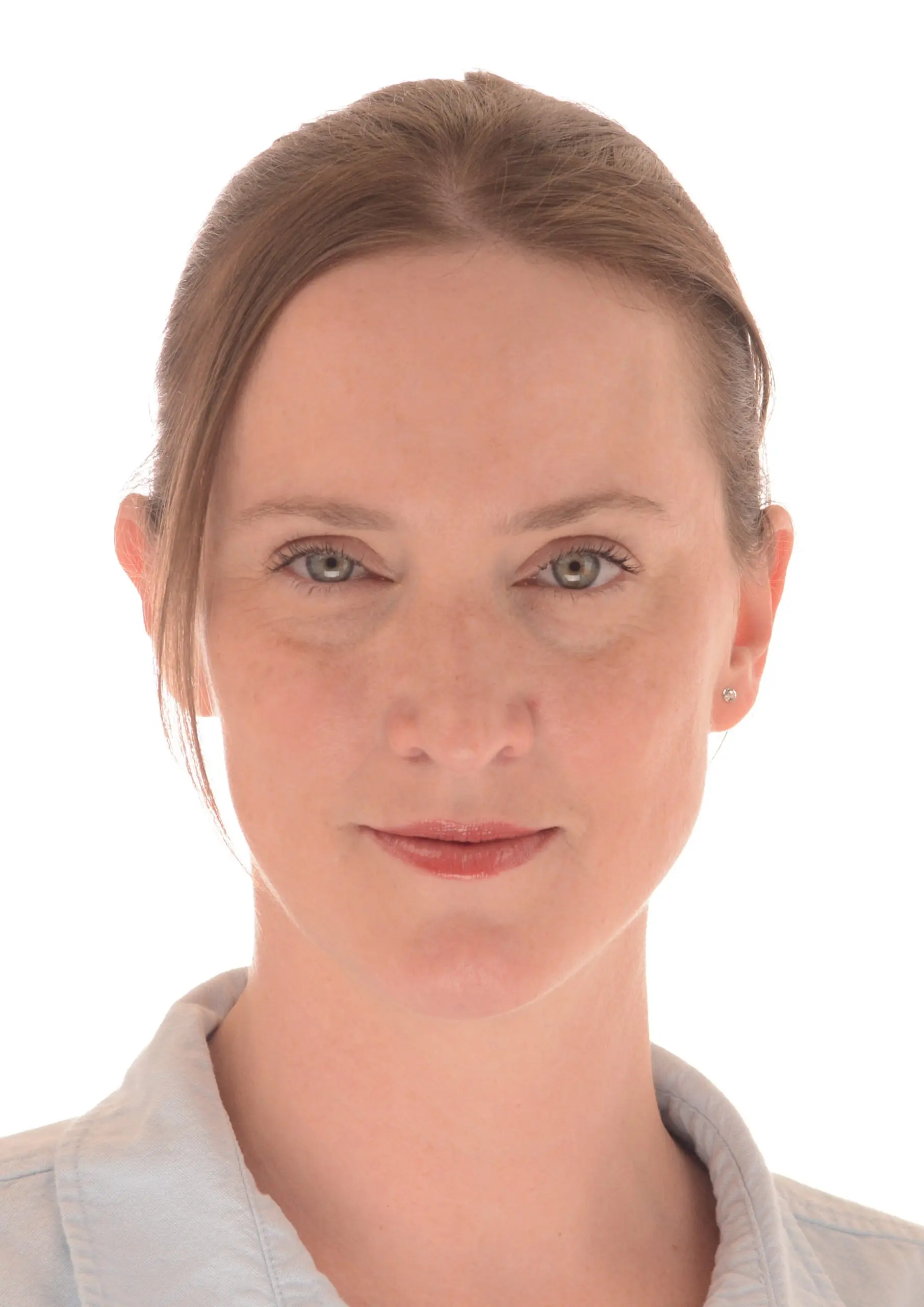 Woman with light skin and brown hair pulled back, wearing a light-colored collared shirt, facing forward against a white background.